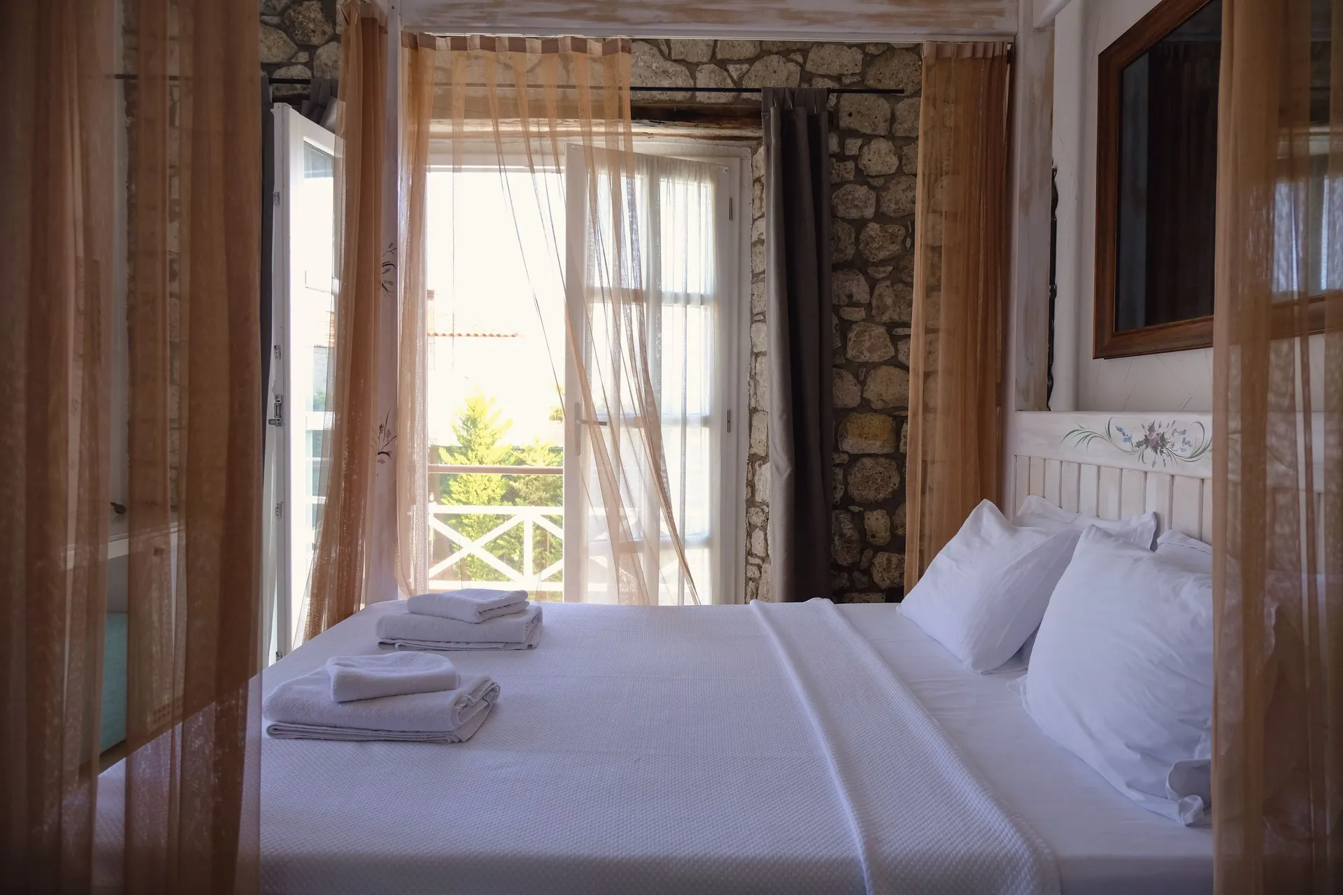 Taş duvarlı, balkon kapısı açık pansiyon odası